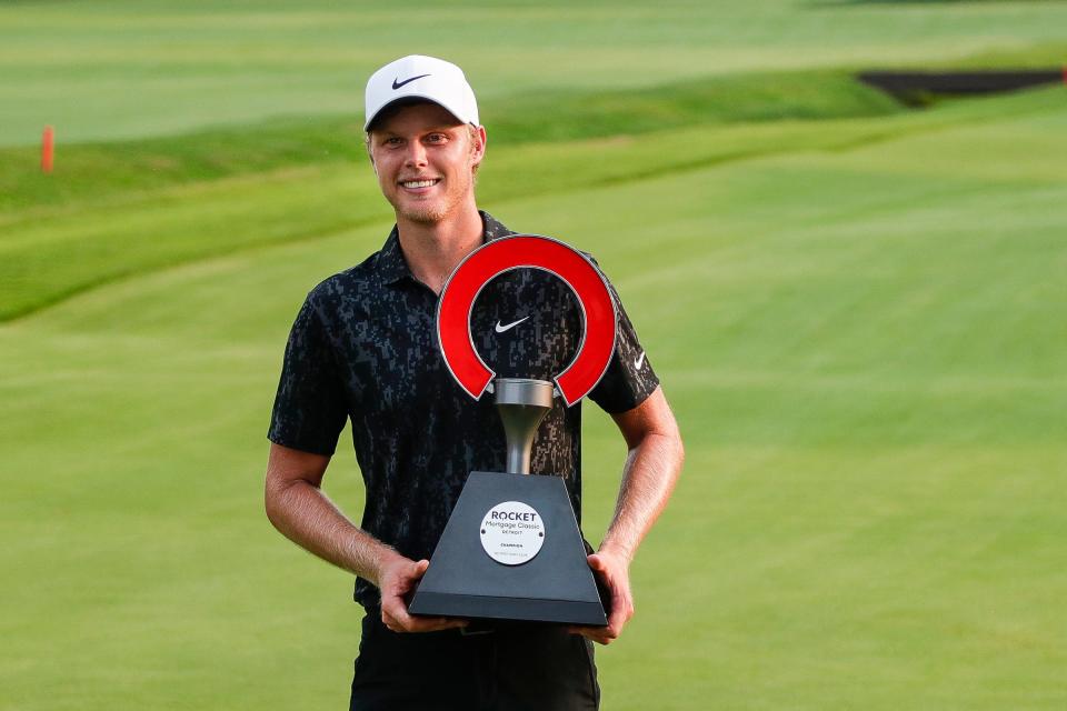 Cam Davis picks up the trophy after winning the Rocket Mortgage Classic in five rounds of playoff at the Detroit Golf Club in Detroit, Sunday, July 4, 2021.