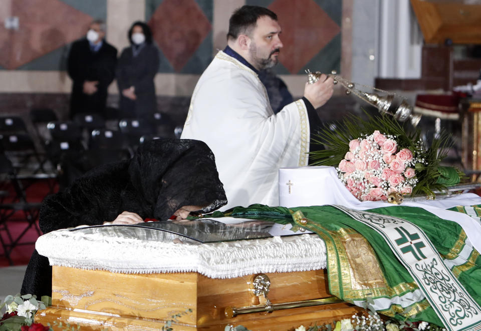 A woman kisses the coffin of Patriarch Irinej during the funeral procession at the St. Sava Temple in Belgrade, Serbia, Sunday, Nov. 22, 2020. The 90-year-old Irinej died early on Friday, nearly three weeks after he led the prayers at a funeral of another senior church cleric in neighboring Montenegro, who also died after testing positive for the virus. (AP Photo/Darko Vojinovic)