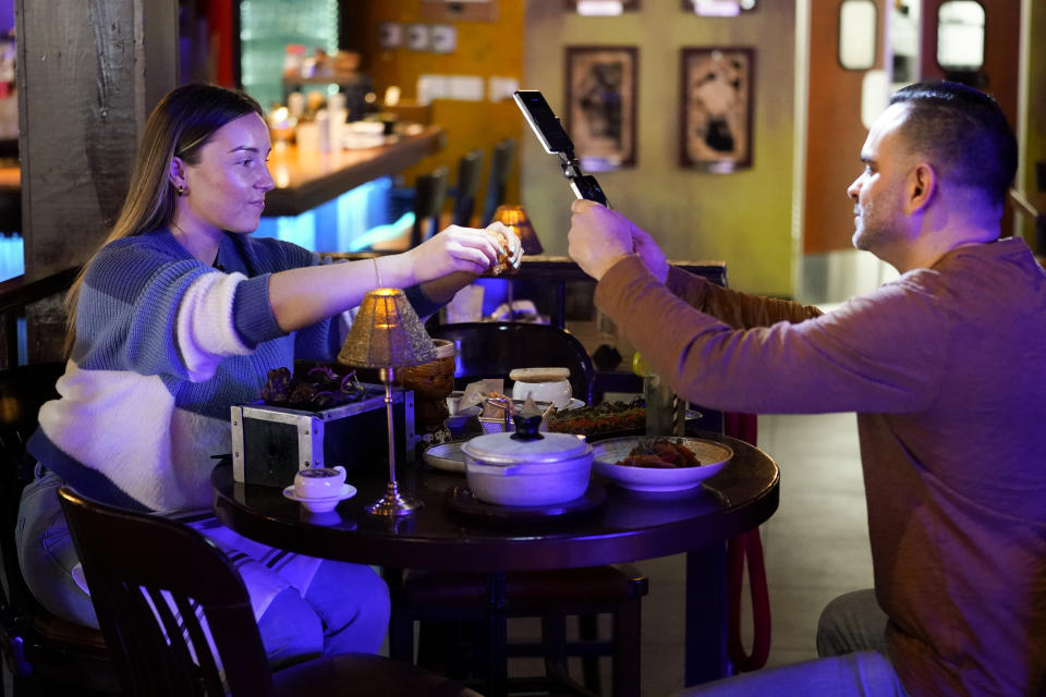 Content creator Jensen Savannah, left, and her fiance and brand manager Jorge Millares, produce a client video at El Puro Cuban Restaurant, Thursday, March 14, 2024, in Charlotte, N.C. (AP Photo/Erik Verduzco)