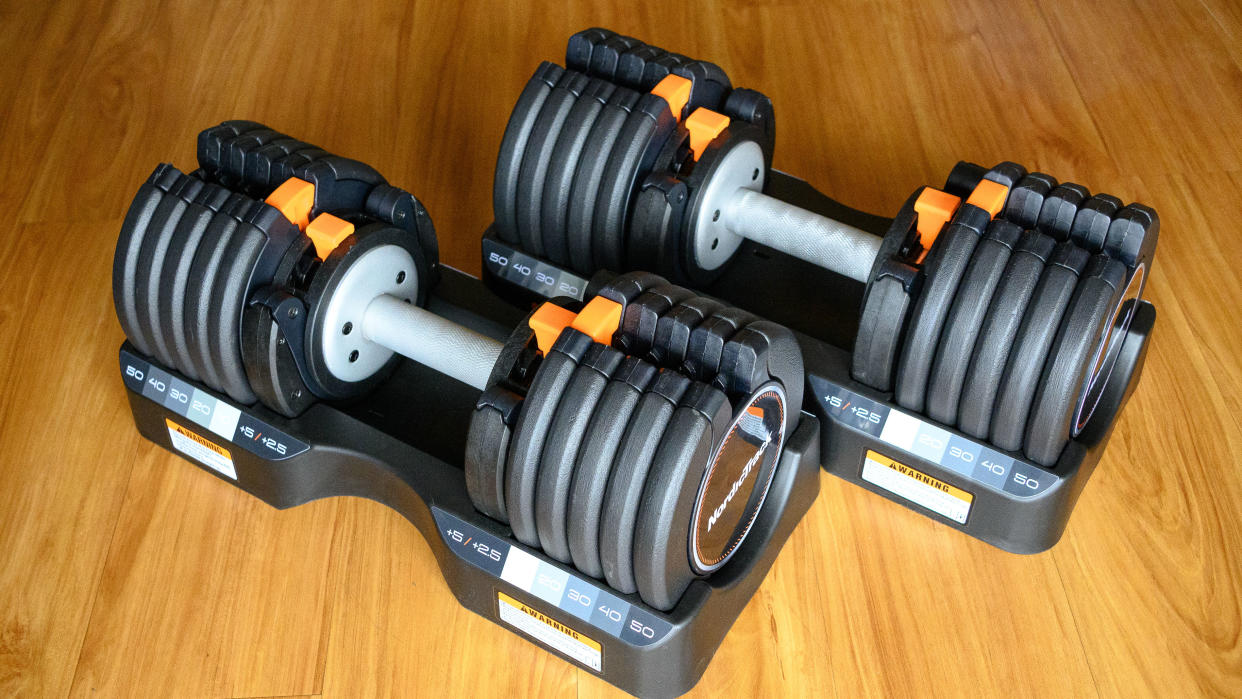  NordicTrack Select-a-Weight Adjustable Dumbbells in the storage tray on a wooden floor. 