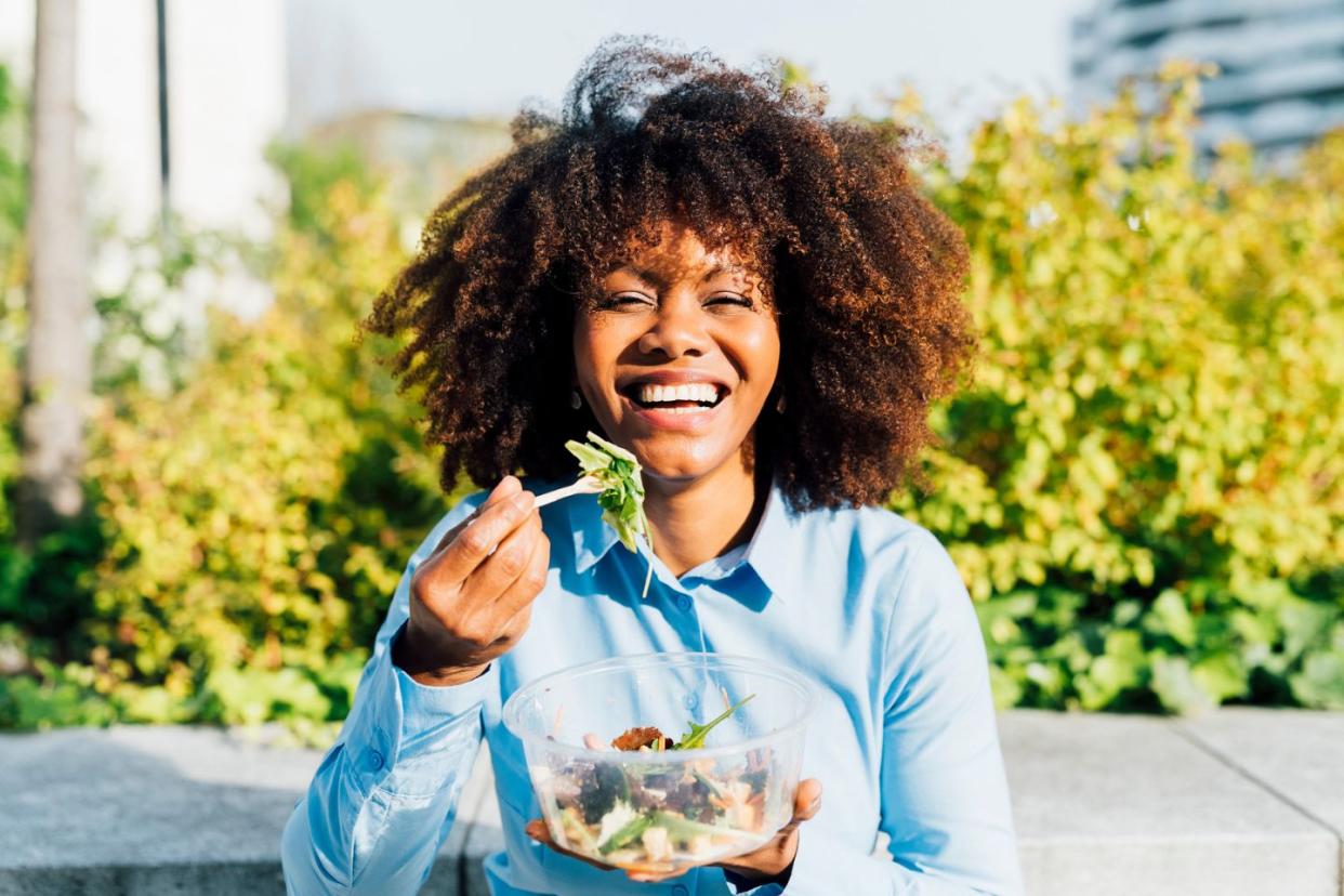 woman smiling while eating a salad