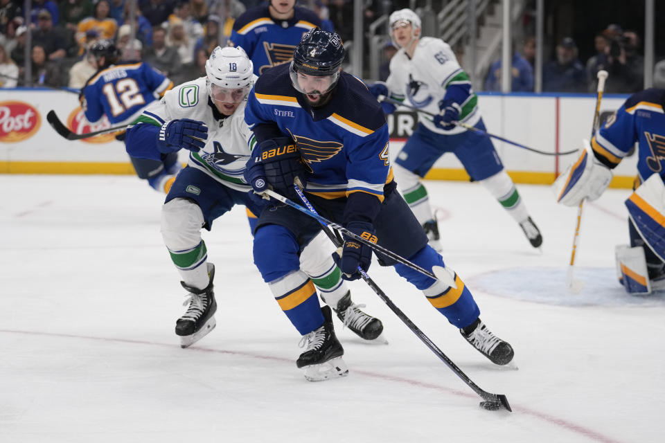 St. Louis Blues' Nick Leddy (4) controls the puck as Vancouver Canucks' Sam Lafferty (18) defends during the third period of an NHL hockey game Thursday, Jan. 4, 2024, in St. Louis. (AP Photo/Jeff Roberson)