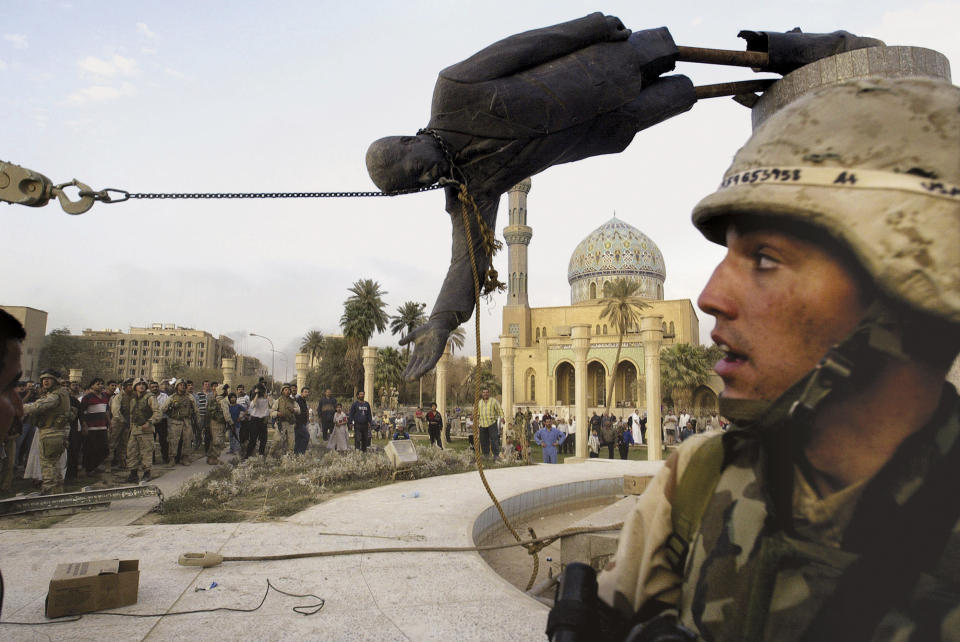 FILE - Iraqi civilians and U.S. soldiers pull down a statue of Saddam Hussein in downtown Baghdad, April 9, 2003. (AP Photo/Jerome Delay, File)