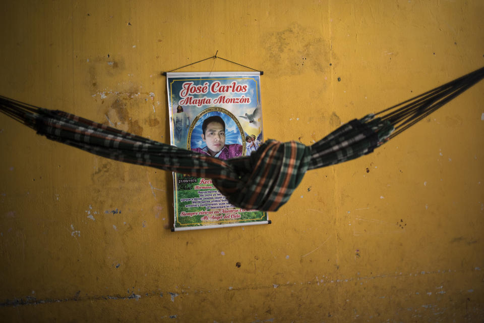 A hammock stretches across a living room in front of a hanging scroll banner honoring COVID-19 victim Jose Mayta, in his home in Iquitos, Peru, Thursday, March 18, 2021. Almost a year ago, Mayta and dozens of other victims were clandestinely buried in a field in Iquitos, a city in Loreto state in the heart of the Peruvian Amazon. (AP Photo/Rodrigo Abd)