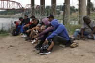 Migrants who had crossed the Rio Grande river into the U.S., remove their shoelaces and others personal items while under custody of National Guard members as they await the arrival of U.S. Border Patrol agents in Eagle Pass, Texas, Friday, May 20, 2022. As U.S. officials anxiously waited, many of the migrants crossing the border from Mexico on Friday were oblivious to a pending momentous court ruling on whether to maintain pandemic-related powers that deny a chance to seek asylum on grounds of preventing the spread of COVID-19. (AP Photo/Dario Lopez-Mills)