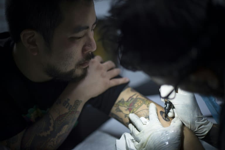 Tattoo artist Luke Satoru gets a number 9 tattooed on his arm by Manu Carrasco to commemorate the late Thai King Bhumibol Adulyadej, in Bangkok