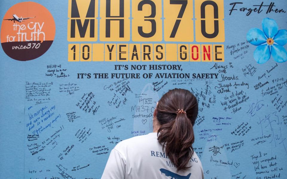 A family member of passengers and crew on the missing Malaysian Airlines flight MH370 writes on a memorial wall during a remembrance event marking the 10th anniversary of the aircraft's disappearance