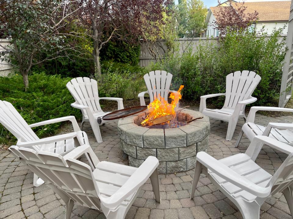 backyard patio with a built-in firepit surrounded by white lawn chairs