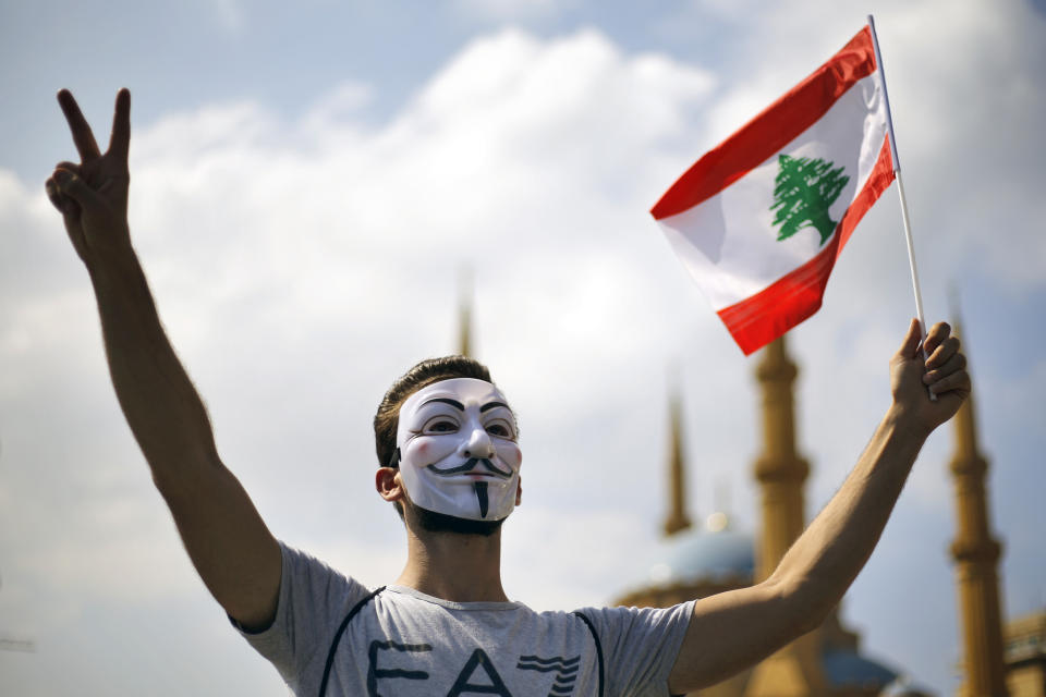 An anti-government protester makes victory sign as he holds a Lebanese flag during a demonstration, in downtown Beirut, Lebanon, Sunday, Sept. 29, 2019. Hundreds of Lebanese are protesting an economic crisis that has worsened over the past two weeks, with a drop in the local currency for the first time in more than two decades. (AP Photo/Bilal Hussein)