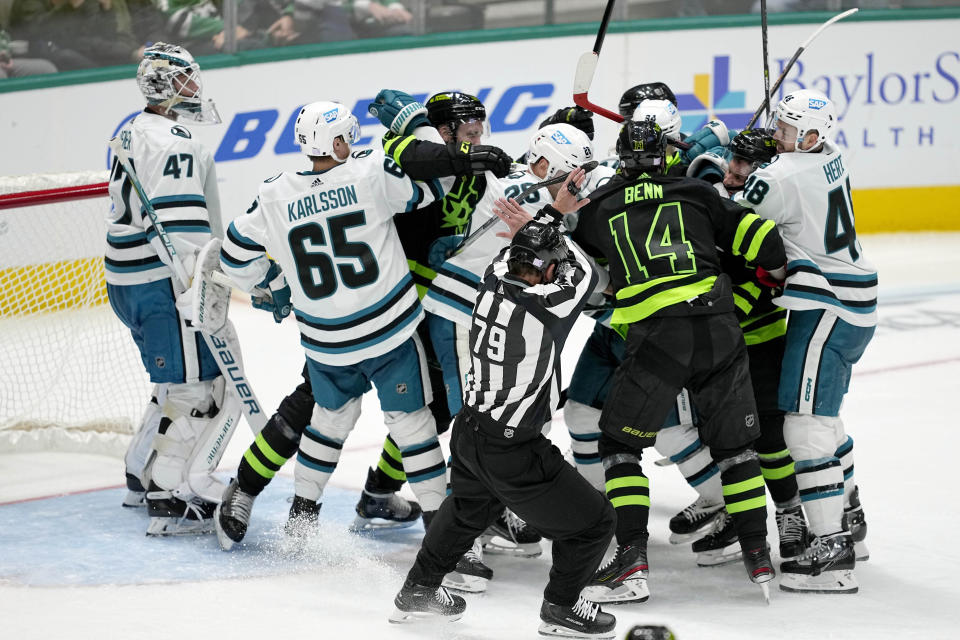 Linesman Kiel Murchison (79) moves in to help break up a large fight between the San Jose Sharks and Dallas Stars in the third period of an NHL hockey game in Dallas, Friday, Nov. 11, 2022. (AP Photo/Tony Gutierrez)