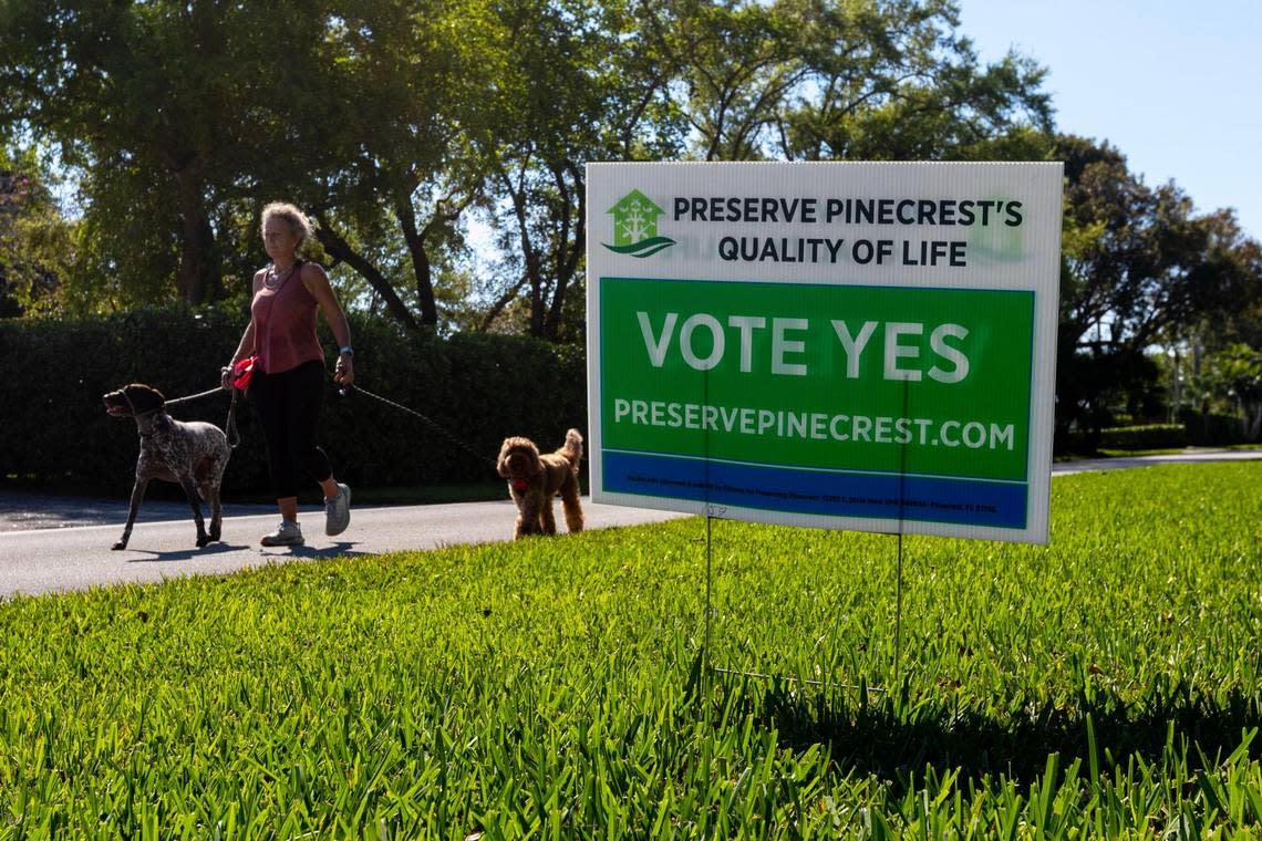 Pinecrest resident Jules Stark walks Charlie and Sienna as she passes by a sign that reads ‘VOTE YES’ sits in front of a resident’s yard in Pinecrest, Florida, on Wednesday, March 1, 2023.