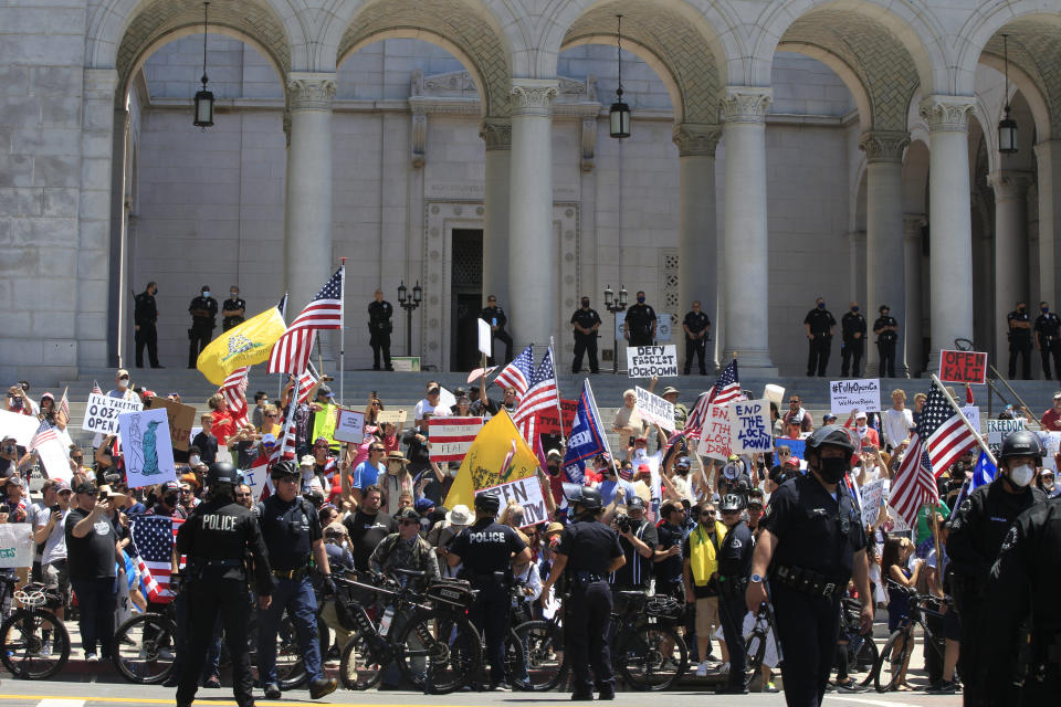 Los Angeles Police officers keep demonstrators off the street as people urge the reopening of businesses during the coronavirus pandemic in front of City Hall in Los Angeles Friday, May 1, 2020. (AP Photo/Damian Dovarganes)