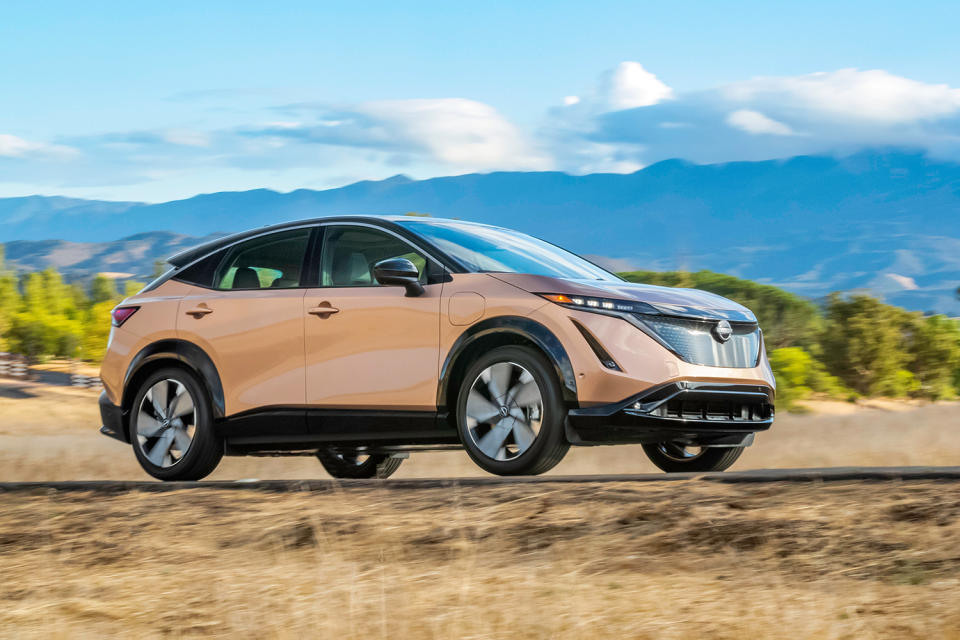 The new electric crossover from Nissan, the Ariya, driving in the sunlight with mountains in the background