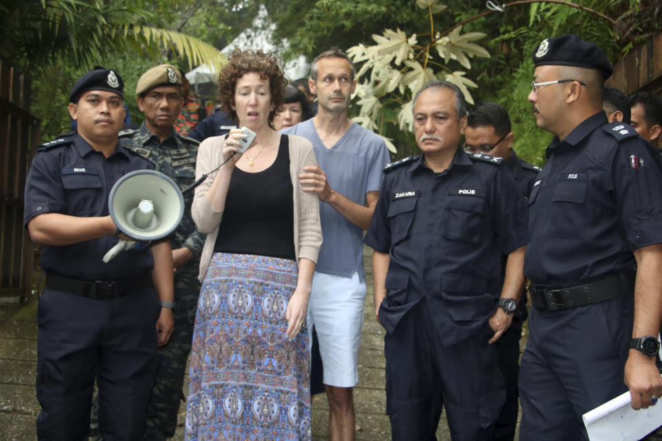 Meabh Quoirin, center left, the mother of a missing British girl Nora Anne Quoirin, speaks to police officers as father Sebastien Quoirin, center right, stands beside her, in Seremban, Negeri Sembilan, Malaysia, Saturday, Aug. 10, 2019. The parents of the 15-year-old London girl who disappeared from a Malaysian resort a week ago say she isn't independent and has difficulty walking, in new details to support their conviction that she was abducted. (The Royal Malaysia Police via AP)