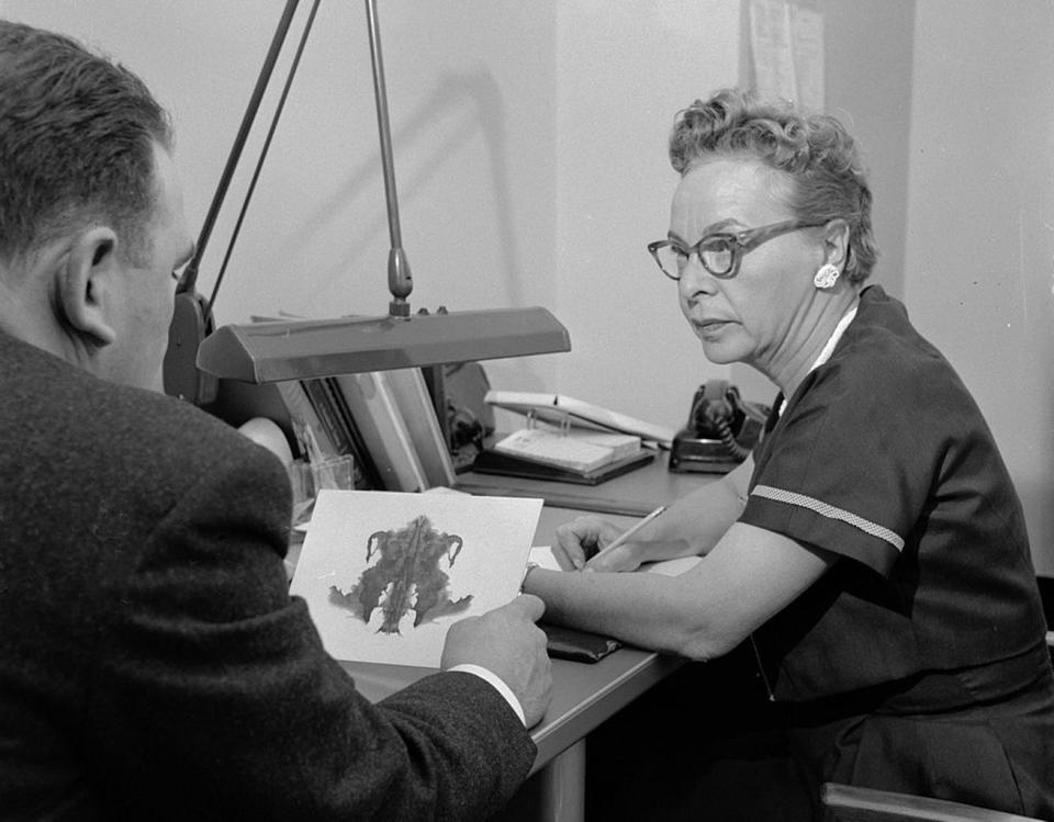 A psychologist at a mental hospital in 1955 discusses a patient's interpretation of an inkblot in the Rorschach test. <cite>Three Lions/Getty Images</cite>