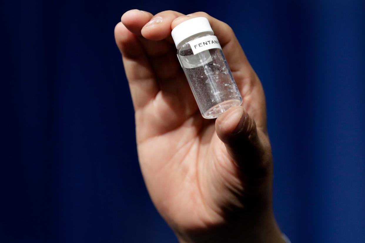 A reporter holds up an example of the amount of fentanyl that can be deadly after a news conference about deaths from fentanyl exposure, at DEA Headquarters in Arlington, Va., June 6, 2017.