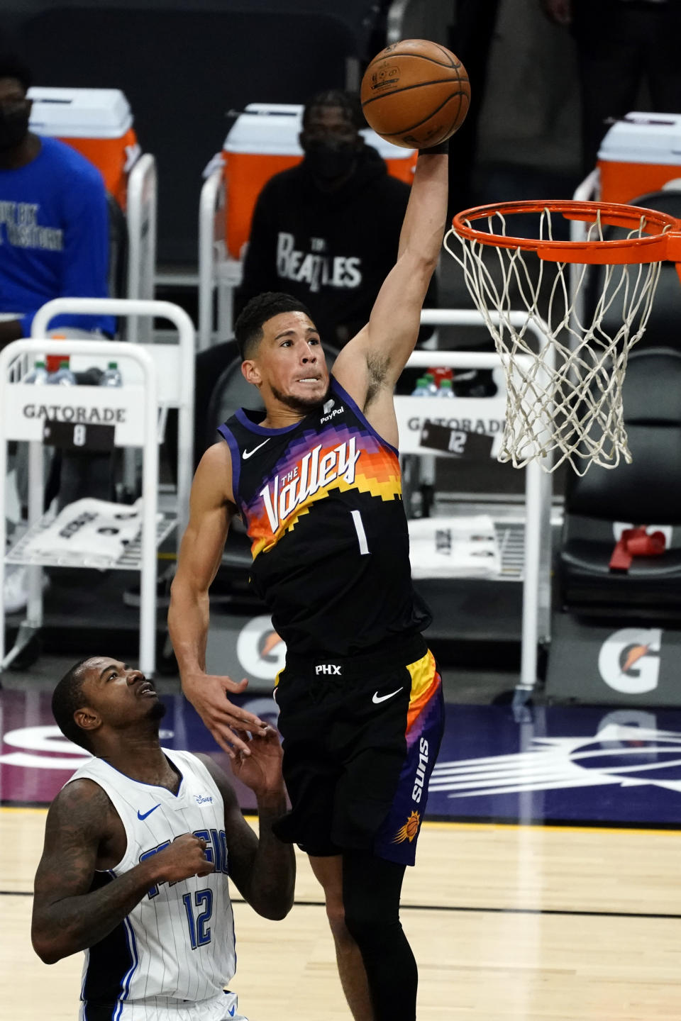 Phoenix Suns guard Devin Booker (1) dunks over Orlando Magic forward Gary Clark during the first half of an NBA basketball game Sunday, Feb. 14, 2021, in Phoenix. (AP Photo/Rick Scuteri)