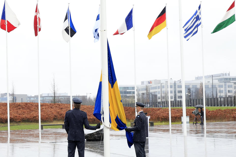 Dos militares se preparan para izar la bandera de Suecia en una ceremonia para conmemorar la entrada del país en la OTAN, en la sede de la OTAN, el lunes 11 de marzo de 2024. (AP Foto/Geert Vanden Wijngaert)