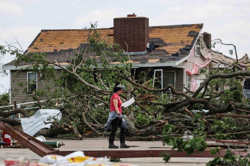 <p>Mike Simons/Tulsa World via AP</p> Rachael Cavin helps clean up storm damage at the Baldridge family home in Pryor, Okla., on May 26.