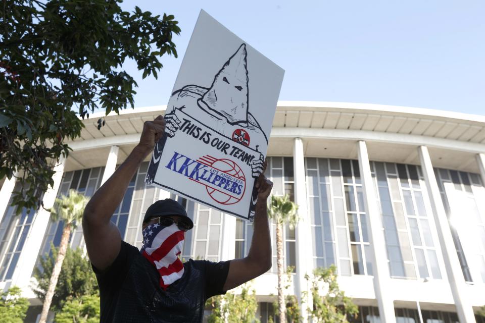 A protester stands outside a court in Los Angeles, California July 7, 2014. The $2 billion sale of the NBA's Los Angeles Clippers faces a key legal hurdle on Monday as the estranged husband and wife who own the franchise battle in court over control of the team. Shelly Sterling, 79, has asked a Los Angeles judge to confirm her as having sole authority to sell the pro basketball franchise to former Microsoft Corp chief executive Steve Ballmer at an NBA-record price after husband Donald Sterling vowed to block the deal. REUTERS/Lucy Nicholson (UNITED STATES - Tags: CRIME LAW SPORT BASKETBALL)