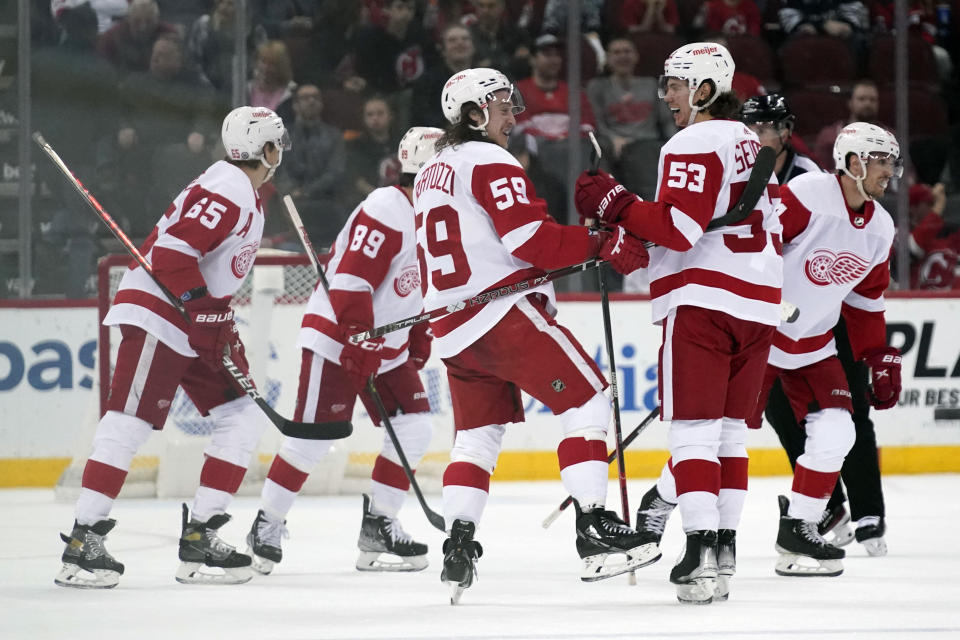 Detroit Red Wings' Tyler Bertuzzi (59), center, celebrates his empty net goal with Moritz Seider (53), second from right, during the third period of an NHL hockey game against the New Jersey Devils in Newark, N.J., Friday, April 29, 2022. The Red Wings defeated the Devils 5-3. (AP Photo/Seth Wenig)