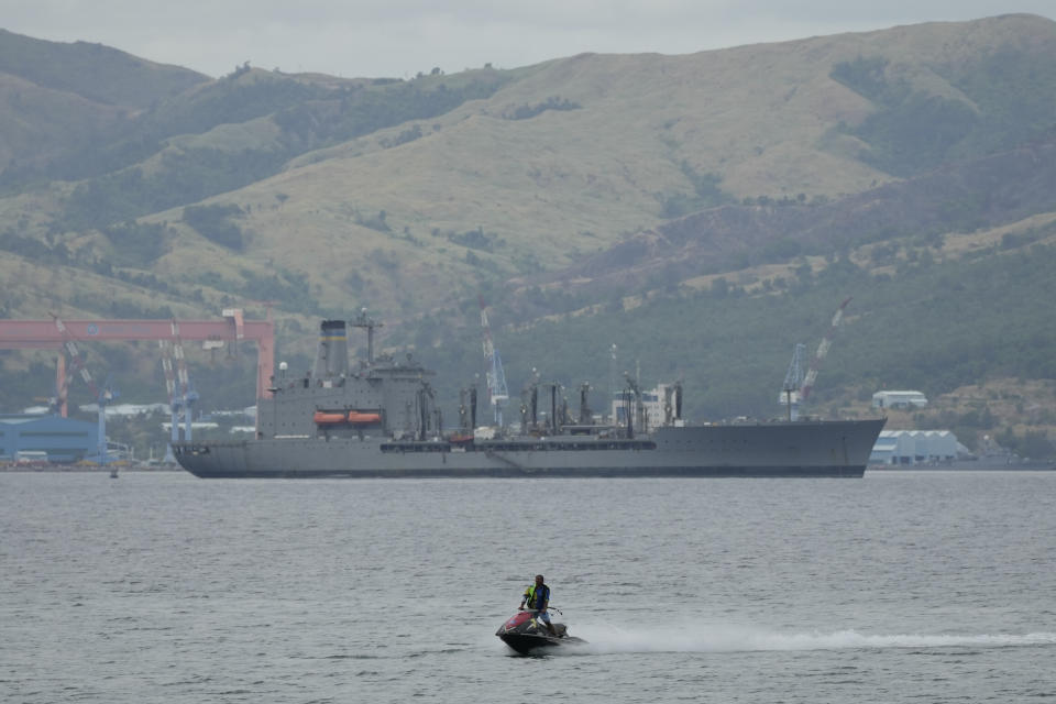 A man on a jetski passes by the USNS Big Horn American supply ship docked near a shipyard in what used to be America's largest overseas naval base at the Subic Bay Freeport Zone, Zambales province, northwest of Manila, Philippines on Monday Feb. 6, 2023. The U.S. has been rebuilding its military might in the Philippines after more than 30 years and reinforcing an arc of military alliances in Asia in a starkly different post-Cold War era when the perceived new regional threat is an increasingly belligerent China. (AP Photo/Aaron Favila)