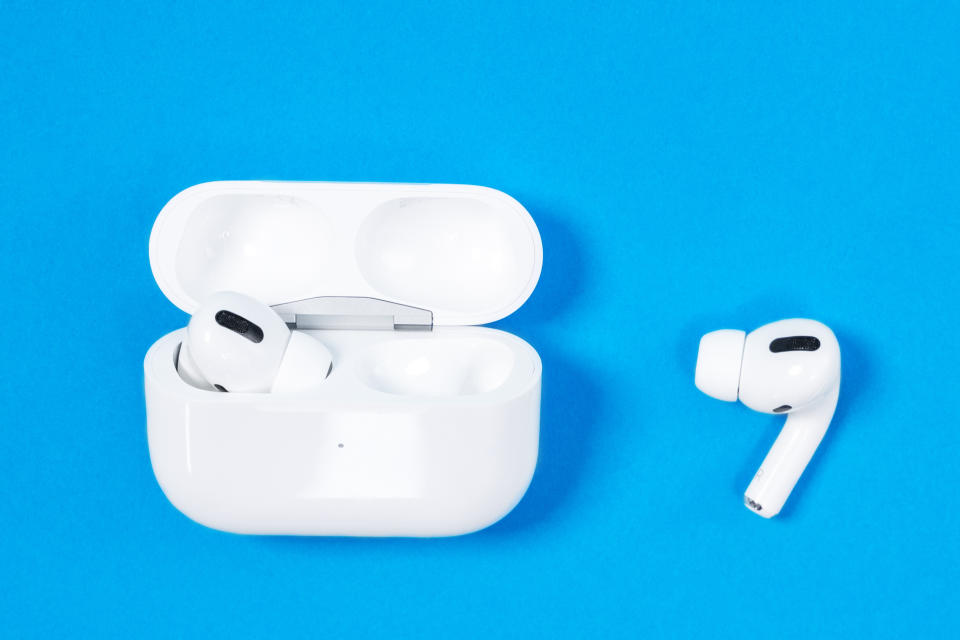 Wireless headphones Apple AirPods Pro in opened charging case with active noise cancellation immersive sound, on blue background