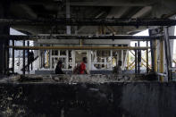 People walk through burnt toll gates with anti police slogans sprayed across, in Lagos Friday, Oct. 23, 2020. Resentment lingered with the smell of charred tires Friday as Nigeria's streets were relatively calm after days of protests over police abuses, while authorities gave little acknowledgement to reports of the military killing at least 12 peaceful demonstrators earlier this week. (AP Photo/Sunday Alamba)