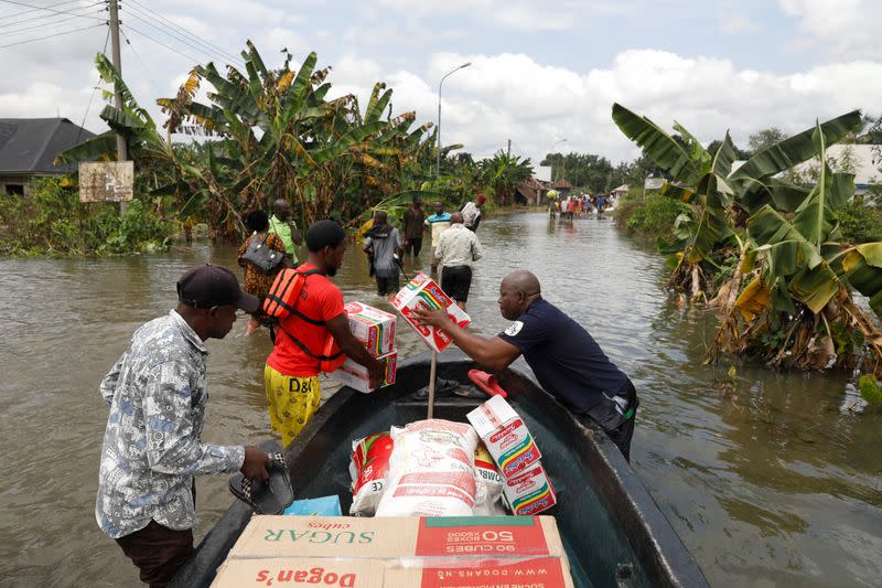 People offload free grocery items they received at a relief camp from a boat, following a massive flood in Obagi community, Rivers state