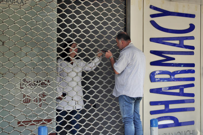 FILE - In this June 11, 2021 file photo, a man speaks with a pharmacist through a closed door after Pharmacies across Lebanon began a two-day strike protesting severe shortages in medicinal supplies that is increasingly putting them in confrontation with customers and patients searching for medicines, in Beirut, Lebanon. Lebanon is struggling amid a 20-month-old economic and financial crisis that has led to shortages of fuel and basic goods like baby formula, medicine and spare parts. (AP Photo/Bilal Hussein, File)