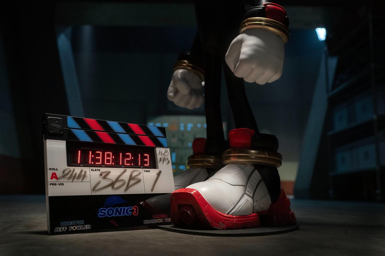 Realistic cartoon character's balled hands and sneaker-shod feet next to a movie-set clapboard.