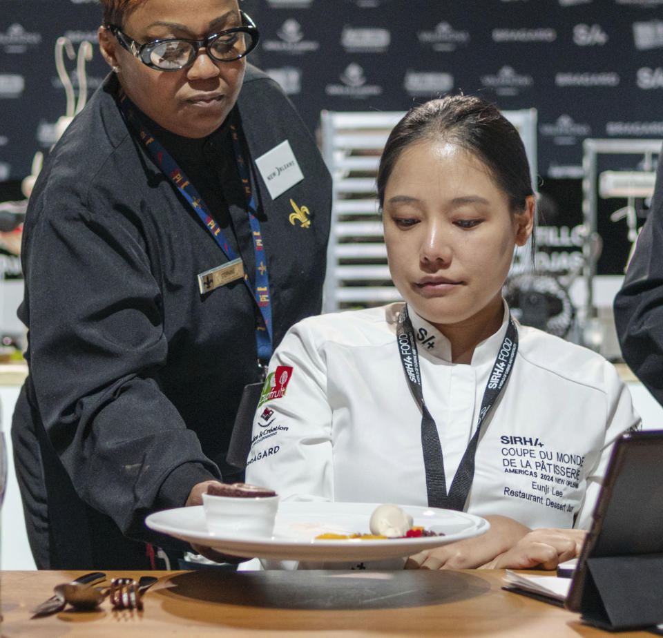 A server places a soufflé in front of jury member Eunji Lee, right, during the Coupe de Monde de la Patisserie, or World Pastry Cup, at the Ernest N. Morial Convention Center in New Orleans, Tuesday, June 11, 2024. (Matthew Perschall/The Times-Picayune/The New Orleans Advocate via AP)