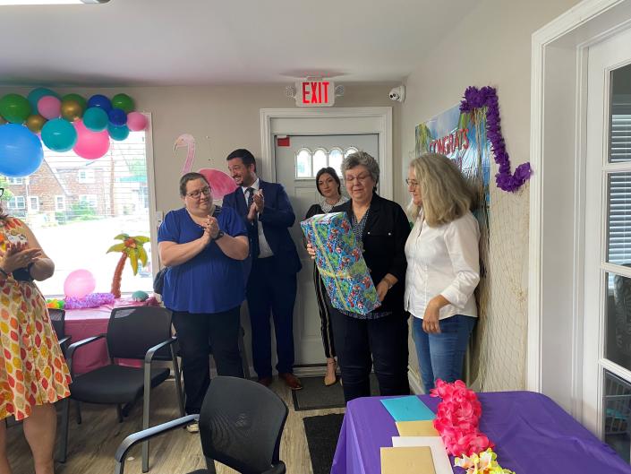 Kathy Ezawa, executive director of the Richland County Domestic Violence Shelter, opens a present Friday during her retirement celebration. Board member Becky Hergatt, far right, presented her with an award to be placed in the new annex building, a project Ezawa spearheaded for the nonprofit agency.