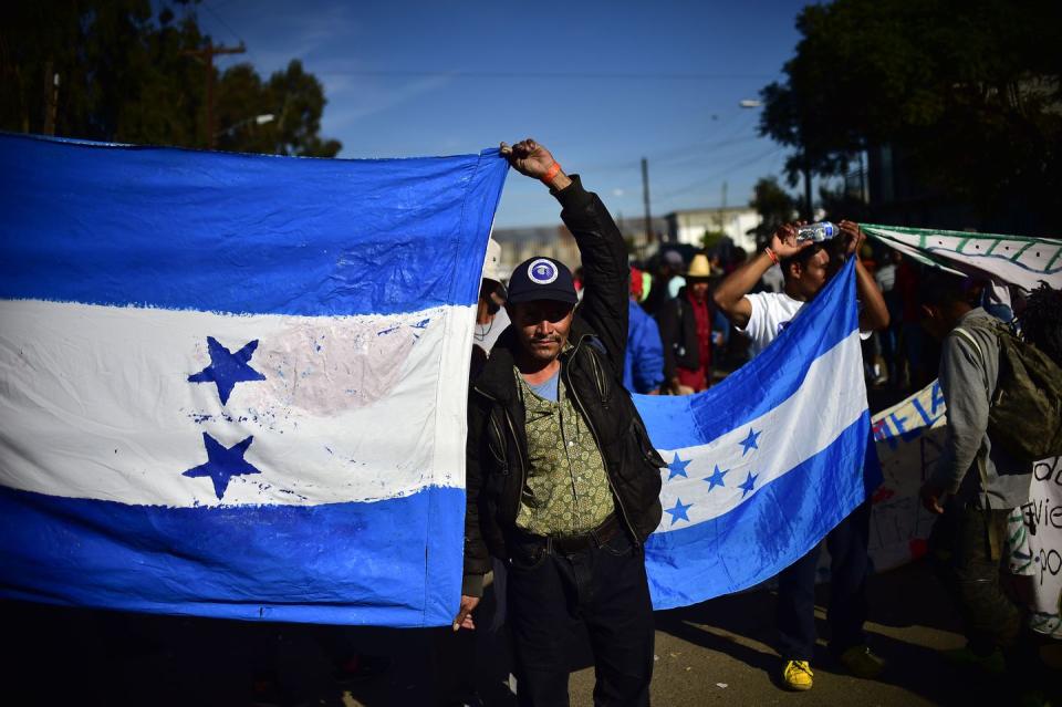 <p>Honduran migrants wanting to reach the United States in hope of a better life, hold their national flag as they leave a shelter in Tijuana, Baja California State, Mexico, and head towards El Chaparral port of entry in the US-Mexico border on November 25, 2018.</p>
