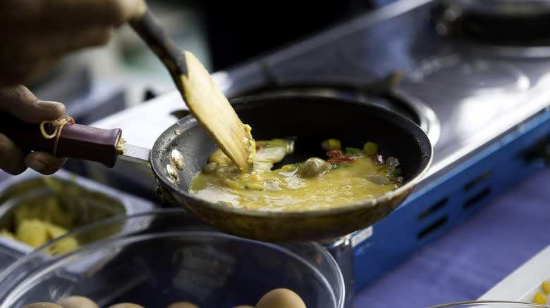 person cooking scrambled eggs