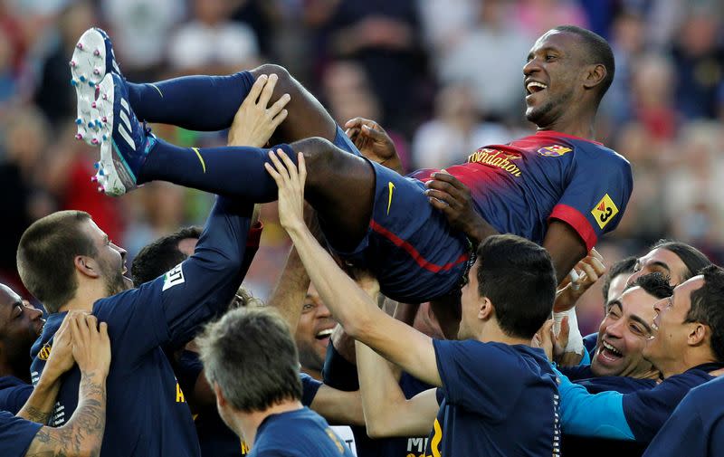 FILE PHOTO: Barcelona defender Eric Abidal is tossed in the air by team mates after the 4-1 victory against Malaga in his last match at the Camp Nou stadium.