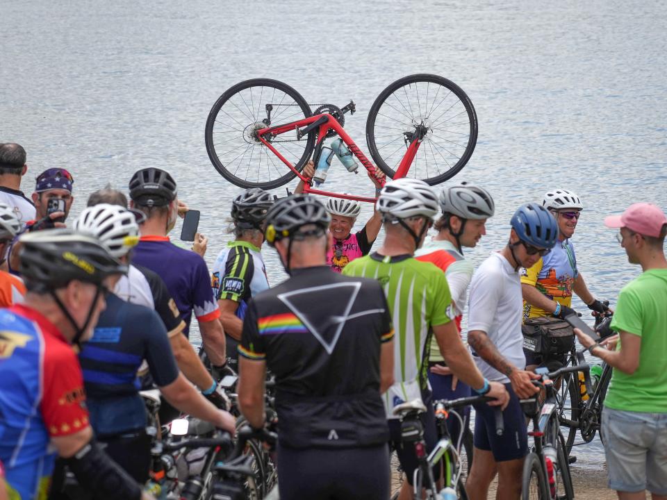 Cyclists stand in line at the tire dip site at the Mississippi River in Davenport during RAGBRAI on Saturday.