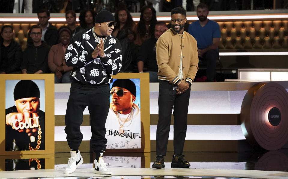 This image provided by CBS shows LL Cool J, left, and host Nate Burleson during an episode of the television game show "Superfan." (Sonja Flemming/CBS via AP)