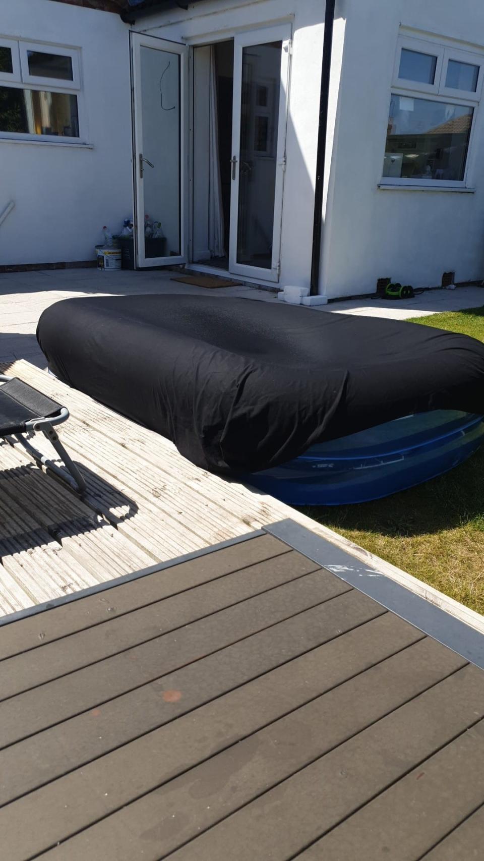 Small blow up pool in backyard of UK home covered with black fitted sheet to keep water warm.