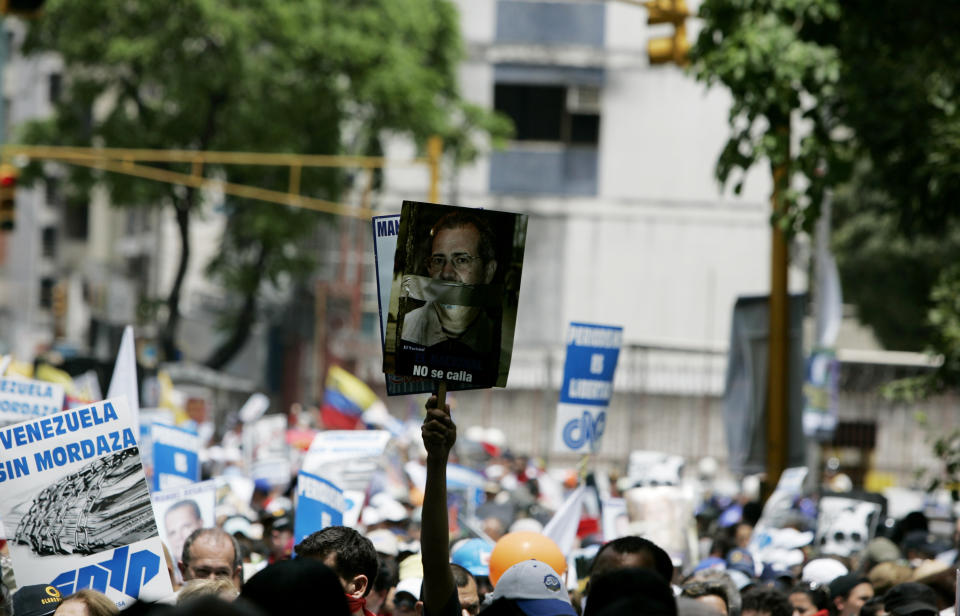 FILE - In this June 27, 2009 file photo, a demonstrator, holding up a sign with an image of Miguel Enrique Otero, director of El Nacional Venezuelan newspaper, with a message that reads in Spanish: "He doesn't shut up," takes part in a march against regulatory official investigations in Caracas, Venezuela. Otero, who ran the last remaining national newspaper critical of the government, was barred in 2015 from leaving Venezuela after the powerful head of the socialist party, Diosdado Cabello, sued him for slander for republishing an article from the Spanish newspaper ABC accusing him of ties to drug cartels. (AP Photo/Fernando Llano, File)