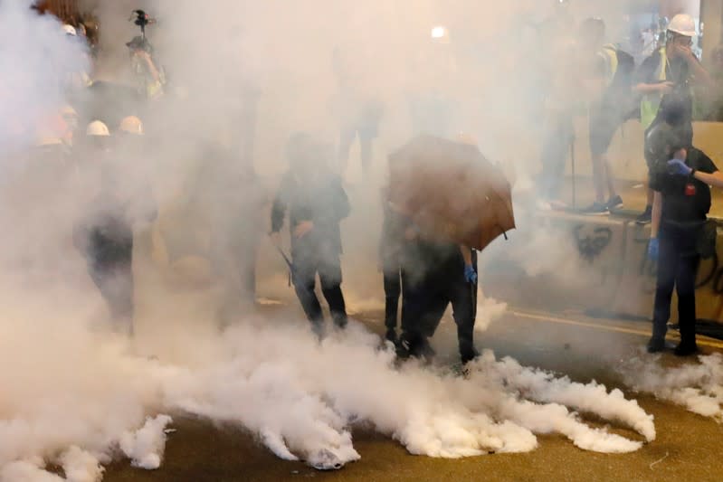 FILE PHOTO: Anti-extradition bill demonstrators react as riot police fire tear gas after a march to call for democratic reforms, in Hong Kong