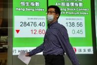 A man wearing a face mask walks past a bank's electronic board showing the Hong Kong share index in Hong Kong, Tuesday, June 22, 2021. Asian shares have rebounded from their retreat a day earlier, tracking Wall Street's recovery from the Federal Reserve's reminder it will eventually provide less support to markets. (AP Photo/Kin Cheung)