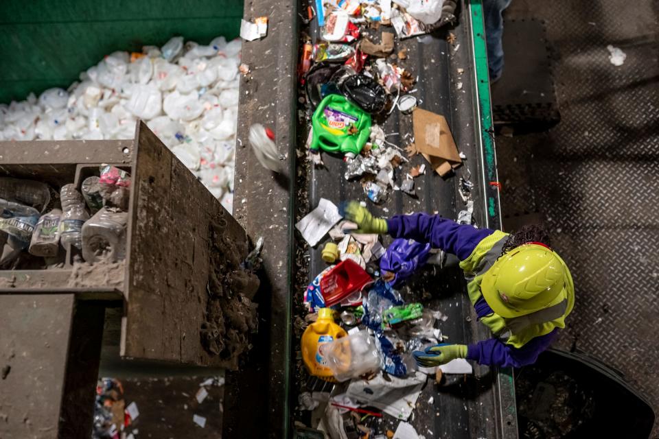 Workers sort through material rapidly moving along belts to pull out plastic items in the recycling process at Resource Recovery and Recycling Authority of Southwest Oakland County in Southfield on Dec. 20, 2022.