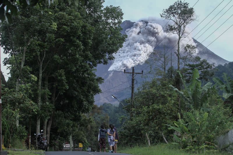 Locals walk on a road as Mount Merapi volcano spews hot ash in Kaliurang, Sleman, Yogyakarta