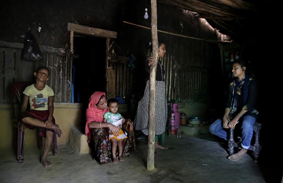 In this Aug. 27, 2018, photo, Rohingya refugee woman Minara Begum, mother of Rahima Akter, sits by her youngest daughter Arohi Zannat inside the family hut in Kutupalong refugee camp, Bangladesh. Begum, 34, a refugee who fled Myanmar as a child and never attended school, not only convinced her husband to let their eldest daughter Rahima study, but she also fought off rebukes from the elders in her community who warned that sending girls out into the world was a sin. (AP Photo/Altaf Qadri)