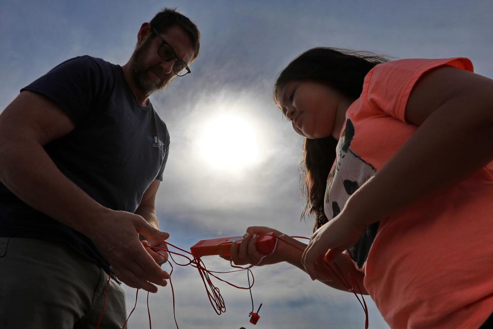 David Zwacki and his daughter Cali Zwacki, 9, untangle the triggering mechanism, before sending their first rocket into the sky at the DYAA field in Dartmouth.