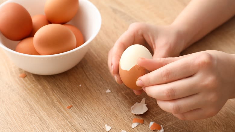 hands peeling boiled eggs