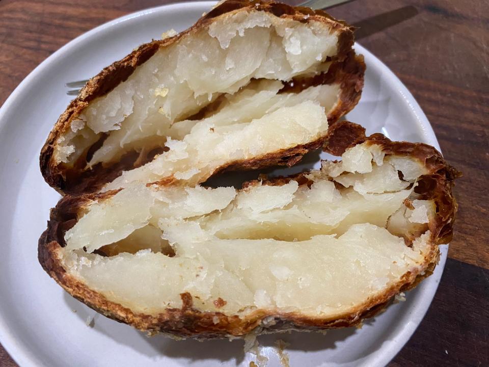 crispy baked potato cut open on a white plate