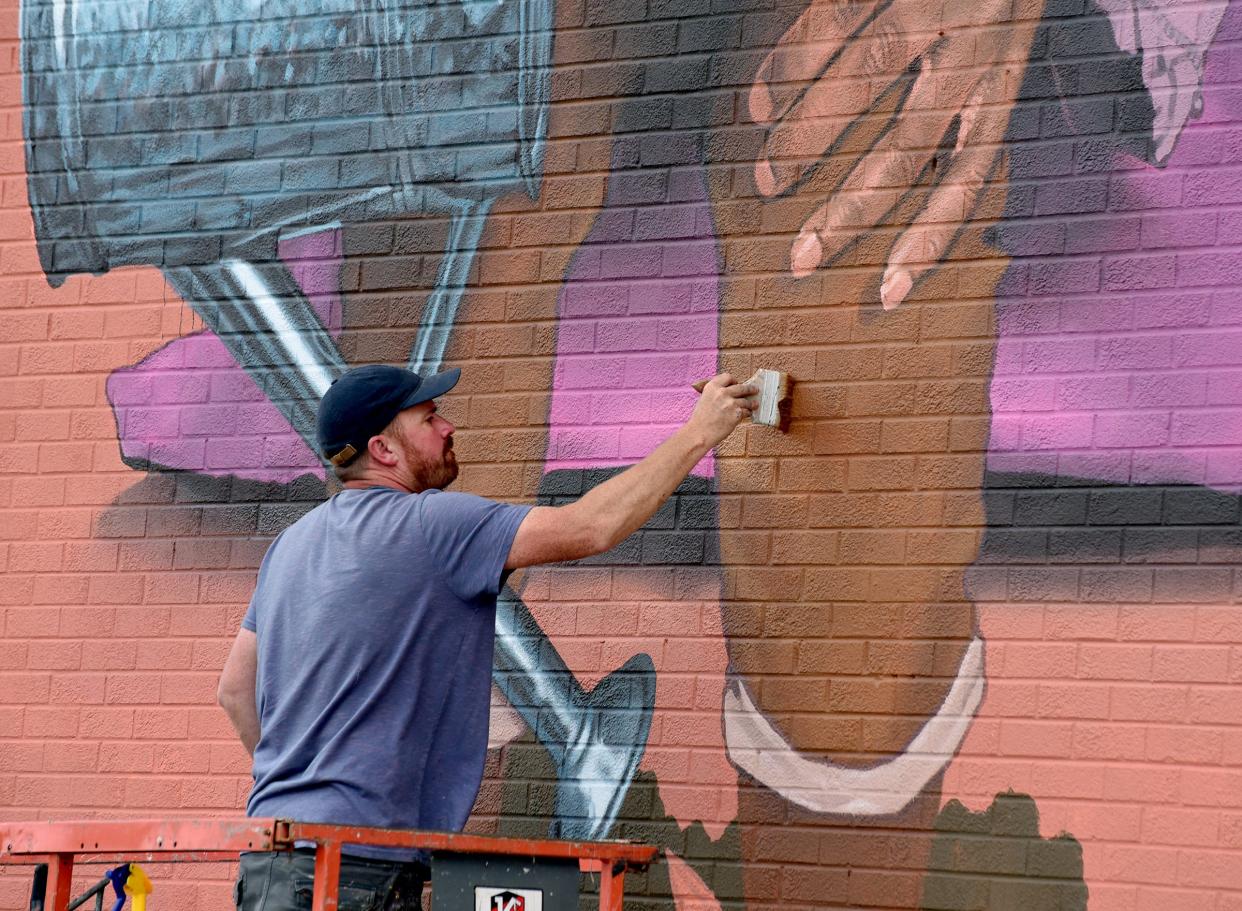 Artist Richard Wilson touches up part of his mural at the Arthur Lesow Community Center in Monroe this past June.
