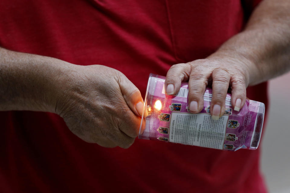 A person lights a candle during a candlelight vigil outside city hall for deceased and injured workers from the Hard Rock Hotel construction collapse Sat., Oct. 12, in New Orleans, on Thursday, Oct. 17, 2019. The vigil was organized by various area labor groups. (AP Photo/Gerald Herbert)